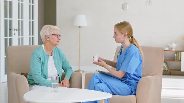 Female doctor shows bottle of medicine to senior patient