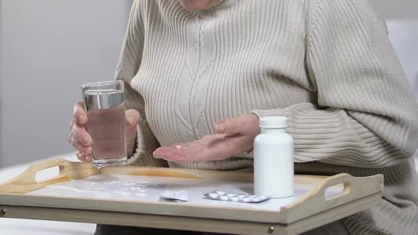 Medical Worker Taking Glass of Water From Lonely Elderly Lady in Nursing Home