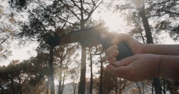 Mature Woman Hands Holding Air Revolver Gun and Aims Target in Forest on Sunset