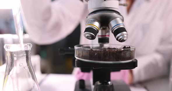 Scientist Adds Clear Liquid From Pipette to Glass Dish Filled with Soil