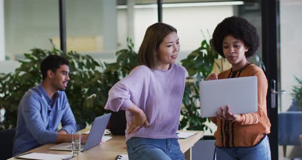 Diverse business people talking using a laptop in modern office