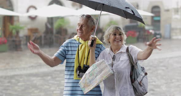 Happy Senior Tourists Stand Downtown and Enjoy the Rainy Weather in Lviv