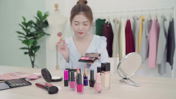Beauty blogger present beauty cosmetics sitting in front camera for recording video.