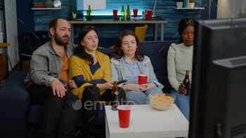 Multi-racial friends changing channels on television until find funny movie