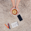 A woman holds hands a cup of tea with lemon, phone, pen and notebook lying on the carpet, top view - PhotoDune Item for Sale