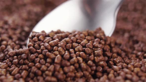 Spooning brown buckwheat tea granules. Falling Asian drink ingredient from a spoon in slow motion
