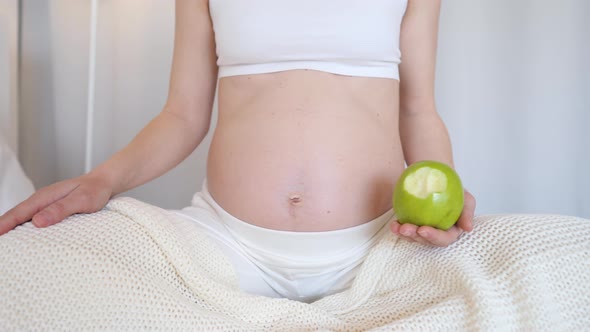 Closeup Of Pregnant Woman Belly With Green Apple