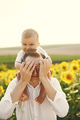 Father holding his son on a shoulders while standing in the sunflowers field - PhotoDune Item for Sale