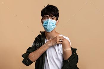 nated against coronavirus, wears adhesive plaster, and feels relieved and ready for the virus. Isolated over beige background, copy space
