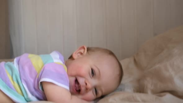 Cute Baby Girl in Striped Shit Lying on Tummy Smiling Laughing and Looking at Camera