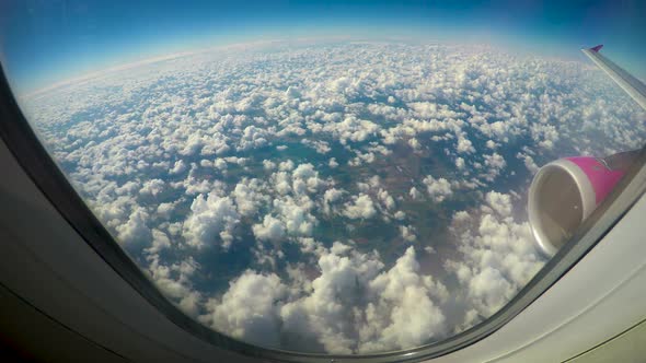 Fluffy clouds viewed from airplane windows, wing and turbine in shot, low cost