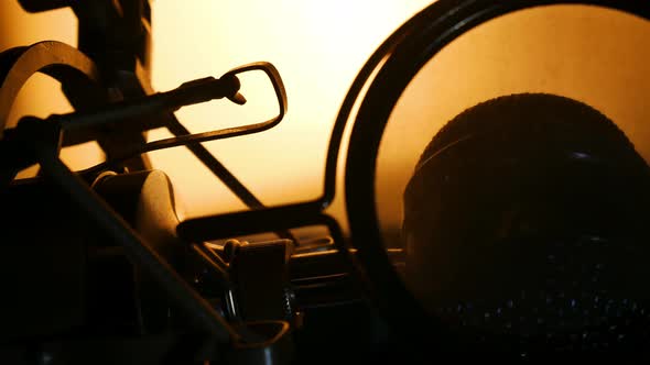 Slow panning right back lit silhouette shot of studio microphone.