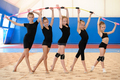 Young female gymnasts making bow with Indian clubs - PhotoDune Item for Sale