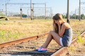 Upset teenager girl sitting on rail track in countryside - PhotoDune Item for Sale