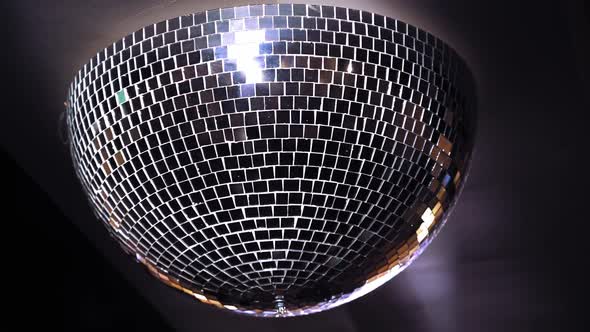 Turning mirror disco ball against dark background