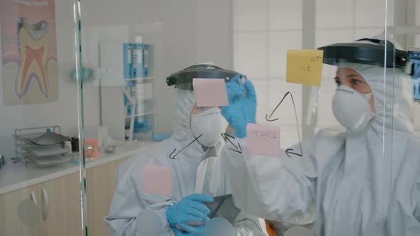 Orthodontists in Ppe Suits Making Diagram with Sticky Notes