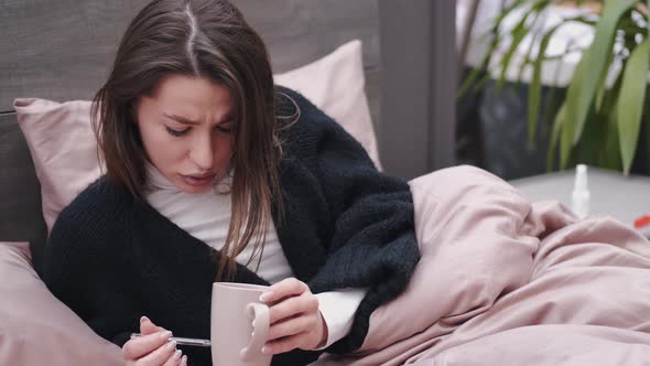 The Woman Feeling Sick Is Lying in Bed and Checking Temperature