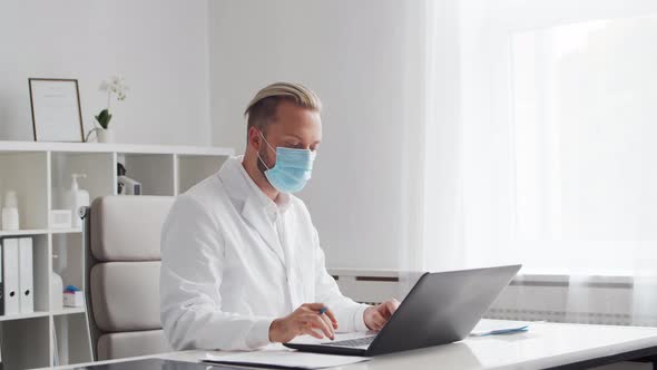 Professional medical doctor is working in hospital office using computer.