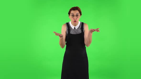 Funny Girl in Round Glasses Is Upset, Waving Her Hands in Indignation, Shrugging. Green Screen