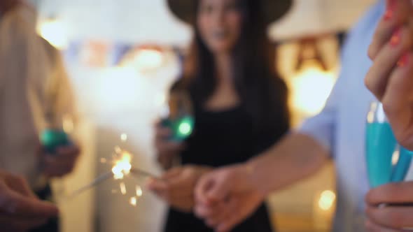 Group of Friends Having Fun With Sparklers and Beverages at Halloween Party