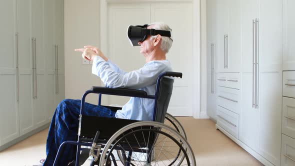 Senior man on wheelchair using vr headset in bedroom