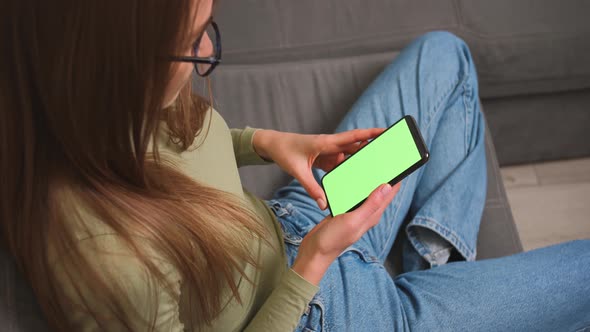 Woman sitting on a couch with Green Screen Smartphone