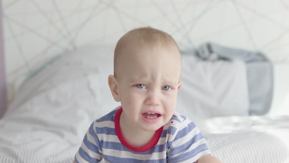 Cute Toddler Boy Child Sad Face Portrait Crying Moody Kid Sitting in Bed Daytime