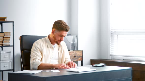 Male manager assistant with beard in yellow shirt sorts small receipts