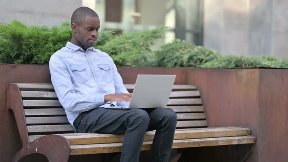 African Man Thinking and Using Laptop Outdoor