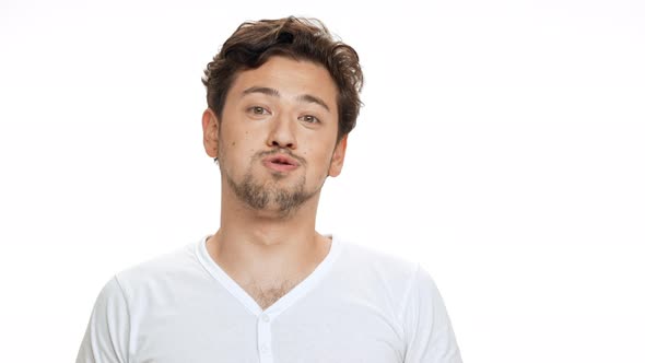 Young Handsome Man Smiling Sighing Looking at Camera Over White Background