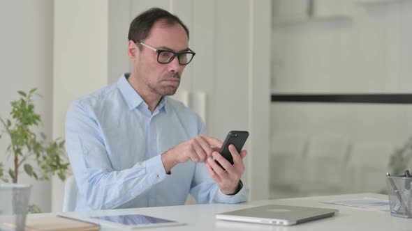 Attractive Middle Aged Man Using Smartphone in Office