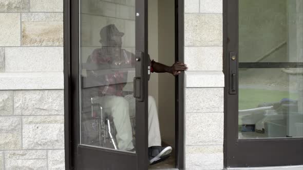 Man in wheelchair exiting building door.