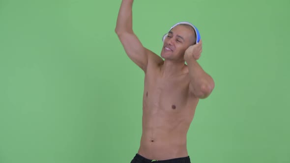 Happy Bald Multi Ethnic Shirtless Man Dancing with Headphones