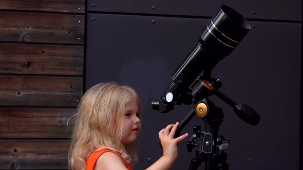 A Little Girl is Looking in a Telescope on a Summer Day