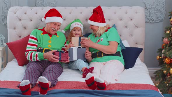 Senior Grandparents with Grandchild Girl Kid Exhcanging Gifts at Home Bedroom Near Christmas Tree