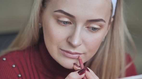 Blonde Girl Apply Lipstick with Cosmetic Pencil on the Lips