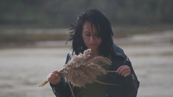 Beautiful Young Woman Walks in the Desert with a Bouquet of Flowers and Spikelets Under Rain