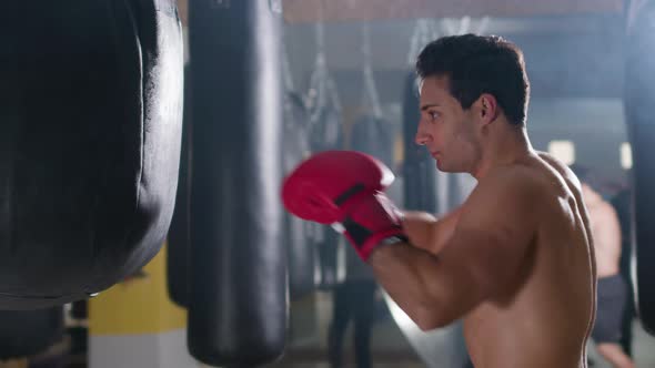 Young Male Boxer Hitting Punching Bag in Gym