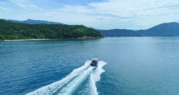 Drone follow Speedboat cruising on the blue sea leaving Foam trails on Water surface, Mountain range