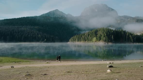 Back view of  happy lover in wild nature, young couple standing and looking at autumn Black lake