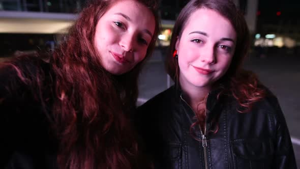 Two young beautiful caucasian women friends taking selfie with smart phone hand hold -