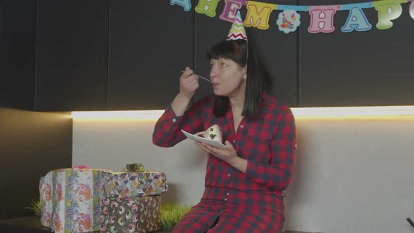 Woman Eating Birthday Cake Alone in Home Kitchen