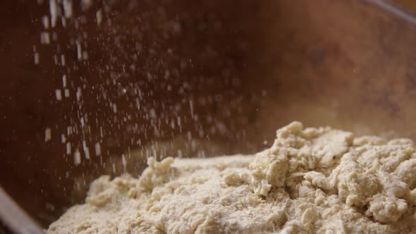 BAKING - Sprinkling flour during sourdough bread baking, slow motion pan right