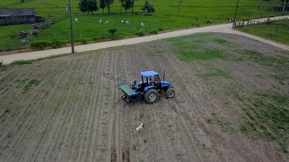 A tractor turns around in a field after having cultivated a row into the dirt AERIAL VIEW