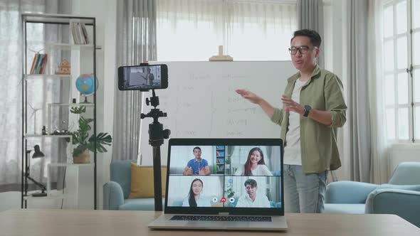 Asian Male Teacher Teaching English Online At Home With Students In Laptop Screen