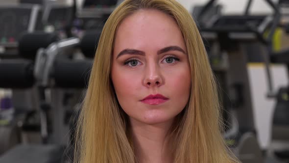 A Young Beautiful Woman Looks at the Camera in a Gym - Face Closeup