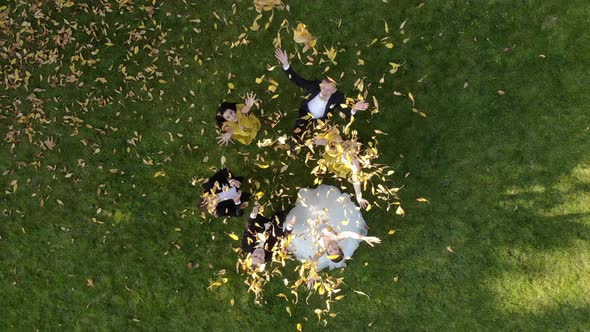 Aerial View Happy Wedding Couple Throws Leaves Up in a Beautiful Autumn Park.