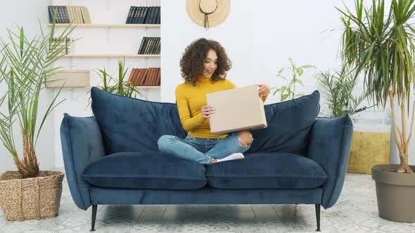 Excited Young Woman Unpacking Huge Carton Box Looking Inside