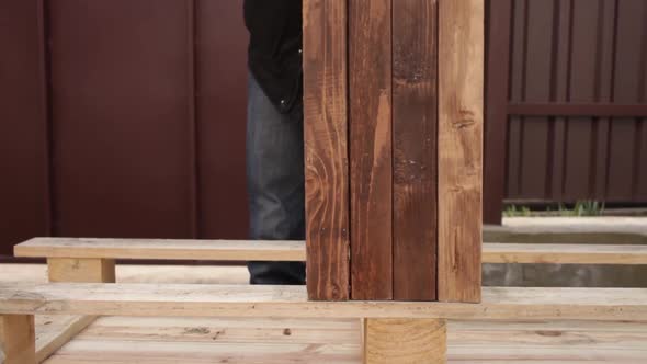 A Man Lays Wooden Boards on the Base for the Table