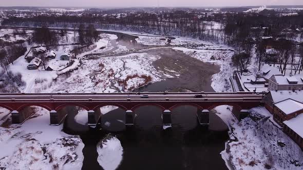 Aerial view of old red brick bridge across the Venta river in Kuldiga, Latvia in overcast winter day